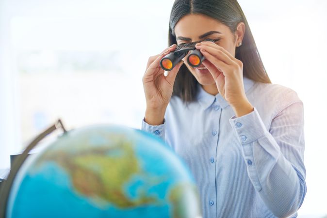 Arab female looking at globe through binoculars
