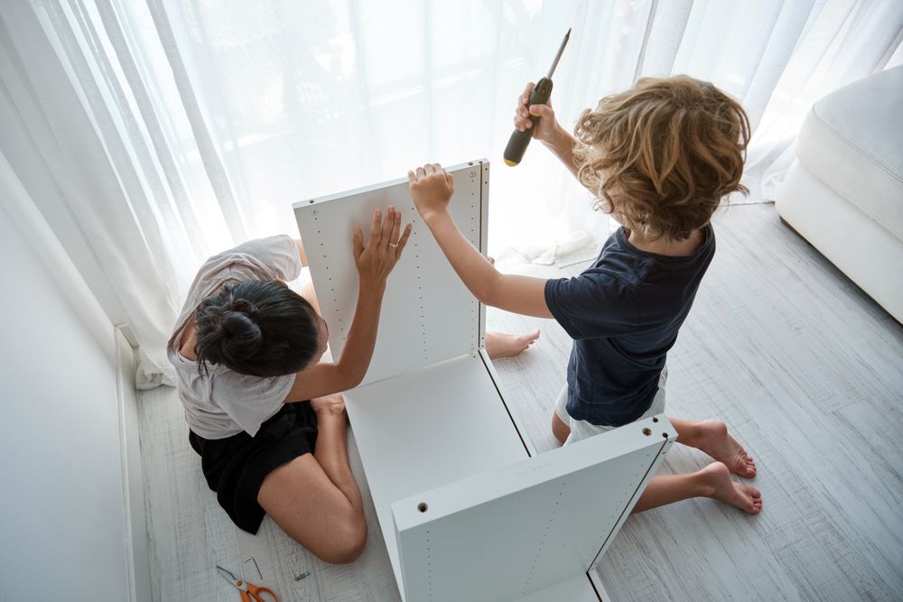 Mother and son assembling wooden furniture in living room