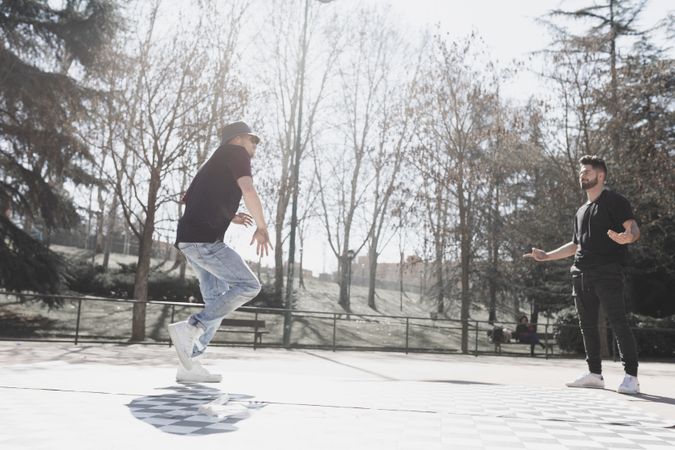 Guy looking at man dancing break dance in park
