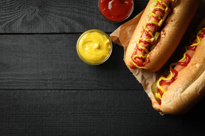 Tasty hot dogs and sauces on wooden background