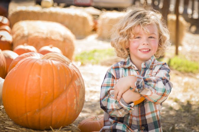 Child Sitting and Holding His Pumpkin Outdoors