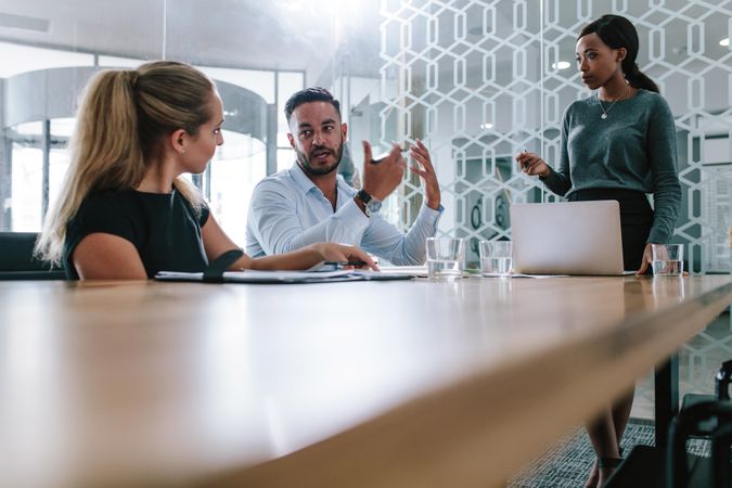 Young man sharing his views with coworkers in boardroom during business meeting