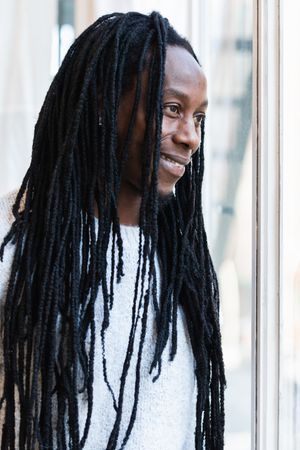 Black man looking at window on street