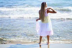 Barefoot Black woman enjoying the coast in colorful dress