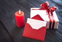 Candle, envelope and present on wooden table