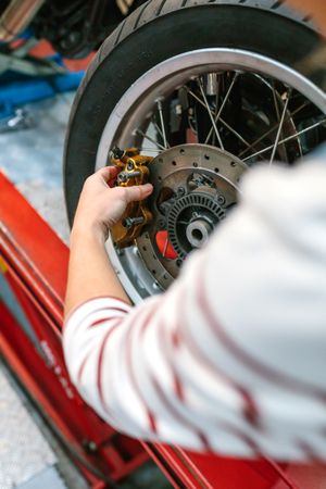Mechanic woman changing caliper brake system in motorbike wheel