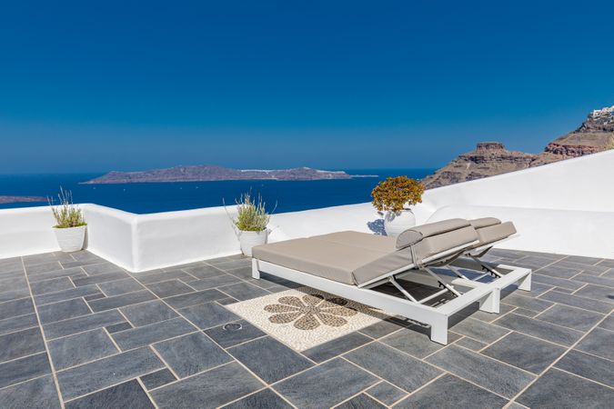 Two reclining chairs on a deck looking over the Aegean Sea