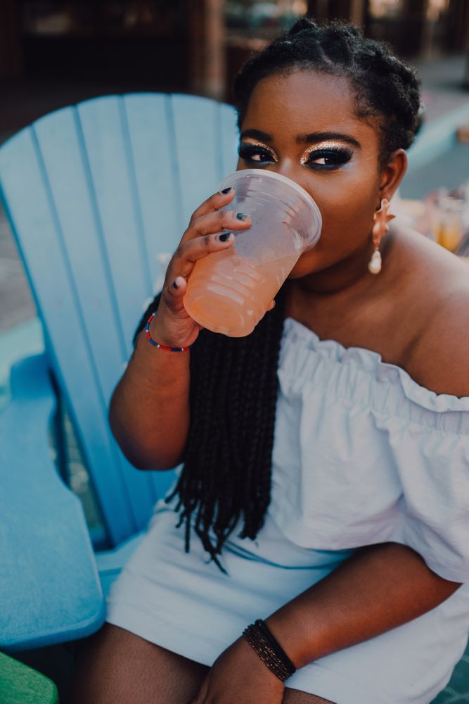 Black modern woman drinking cold beverage at coffee shop