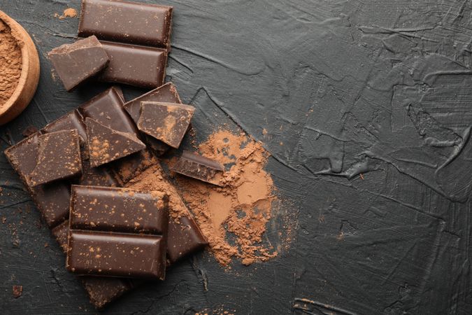 Tasty chocolate and powder on dark background