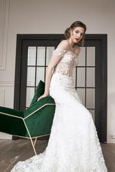 Chic calm woman in white wedding dress leaning on armchair