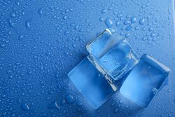 Close up shot looking down at top view of four melting ice cubed on blue table, copy space