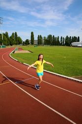Young girl laughing and jogging around a running track