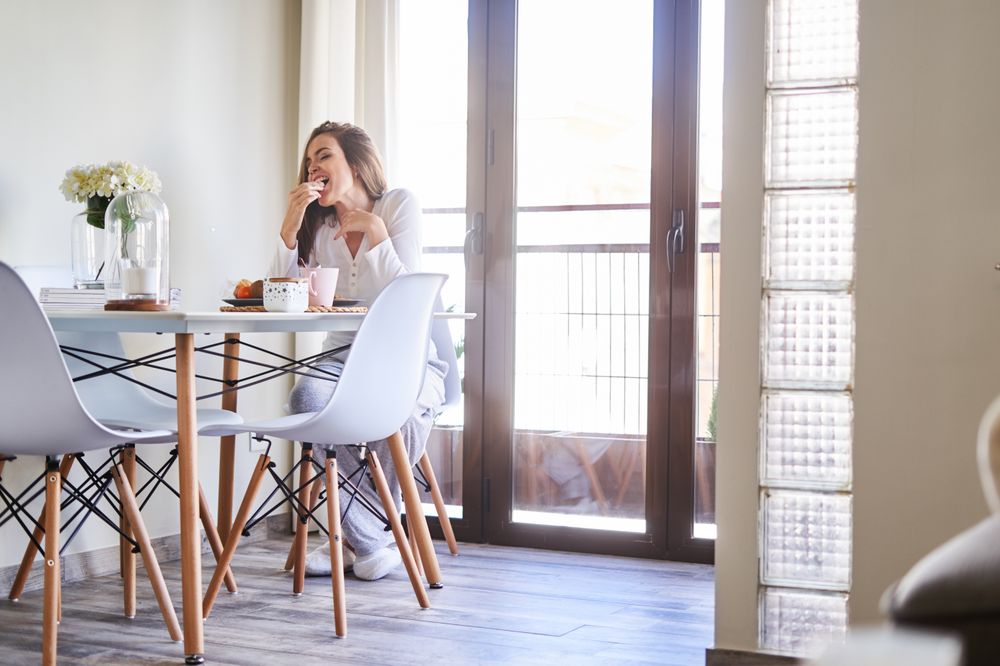 Smiling woman eating at table at home