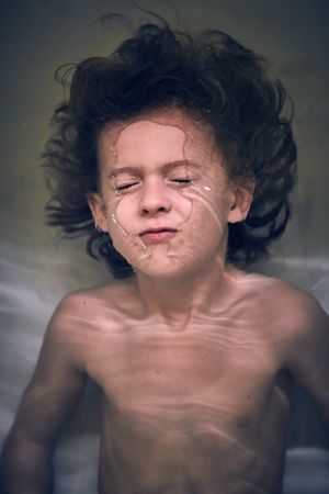Funny little boy diving in bathtub at home