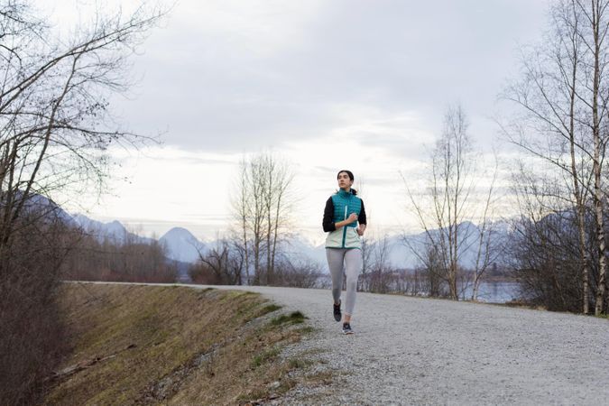 Young female jogging on a lake trail