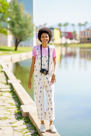 Woman walking along river front in floral overalls