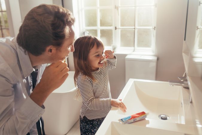 Dad teaching his daughter how to brush teeth