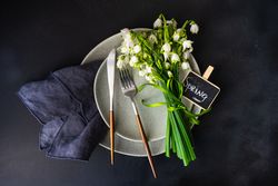 Top view of table setting for spring dinner with flowers on grey plate