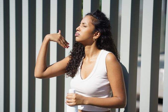 A Confident and Stylish Young Woman is Posing Gracefully Against a Striped Wall Background