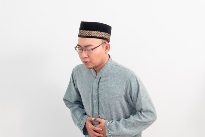 Asian Muslim man feeling touching stomach, hungry during fasting in Ramadan