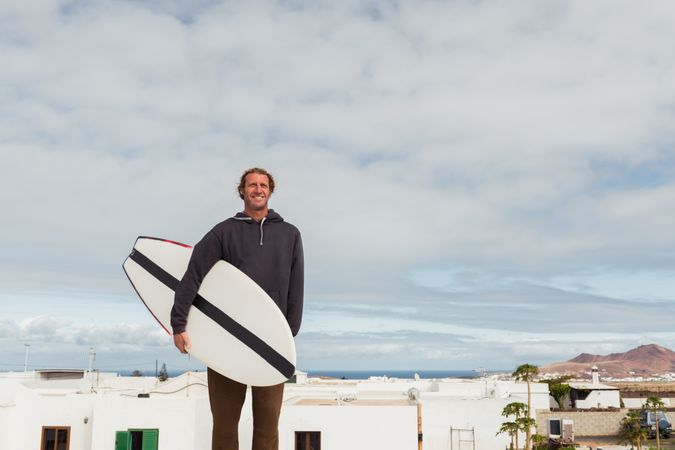 Smiling man standing with surf board