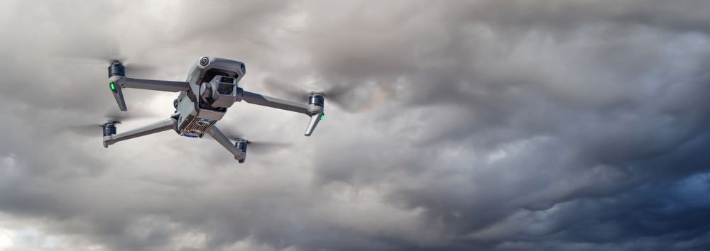 Unmanned Aircraft System (UAV) Quadcopter Drone In The Air On A Cloudy and Stormy Day.