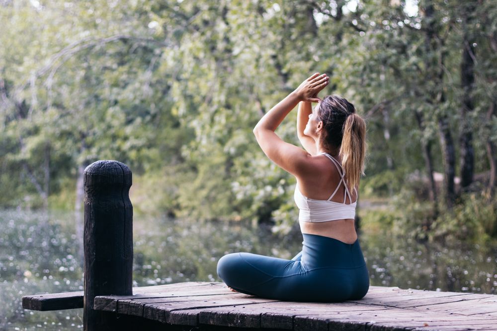 Woman meditating in nature near a lake
