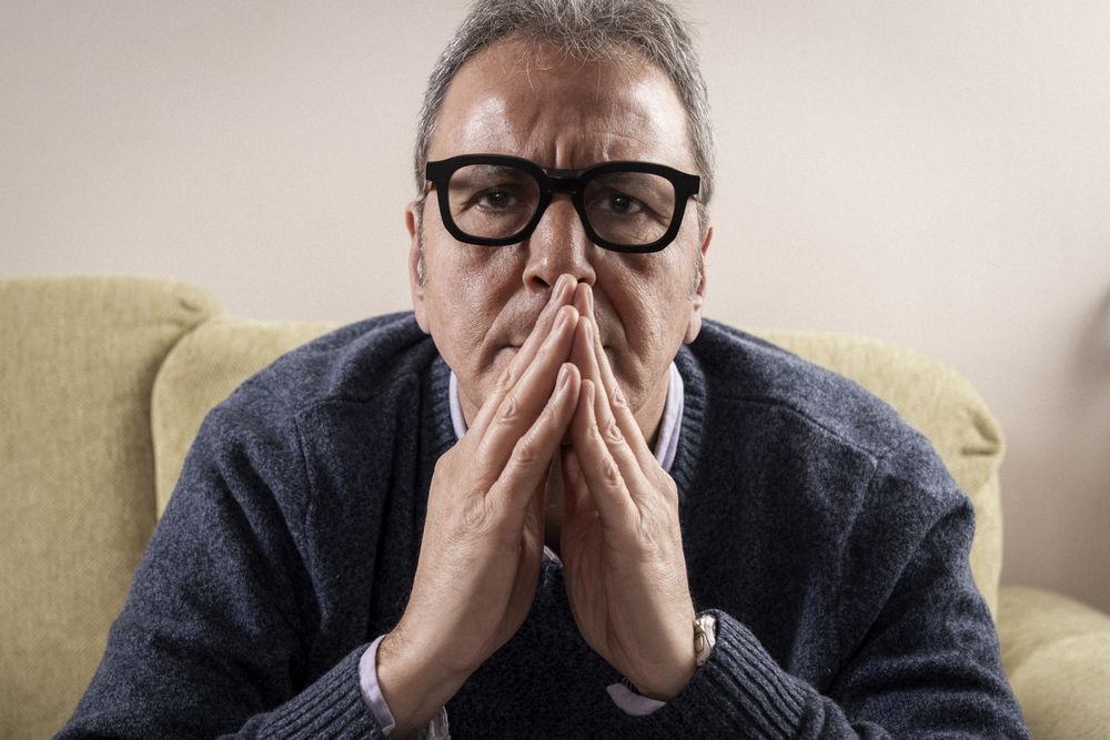 Mature man praying or thinking deeply at home.