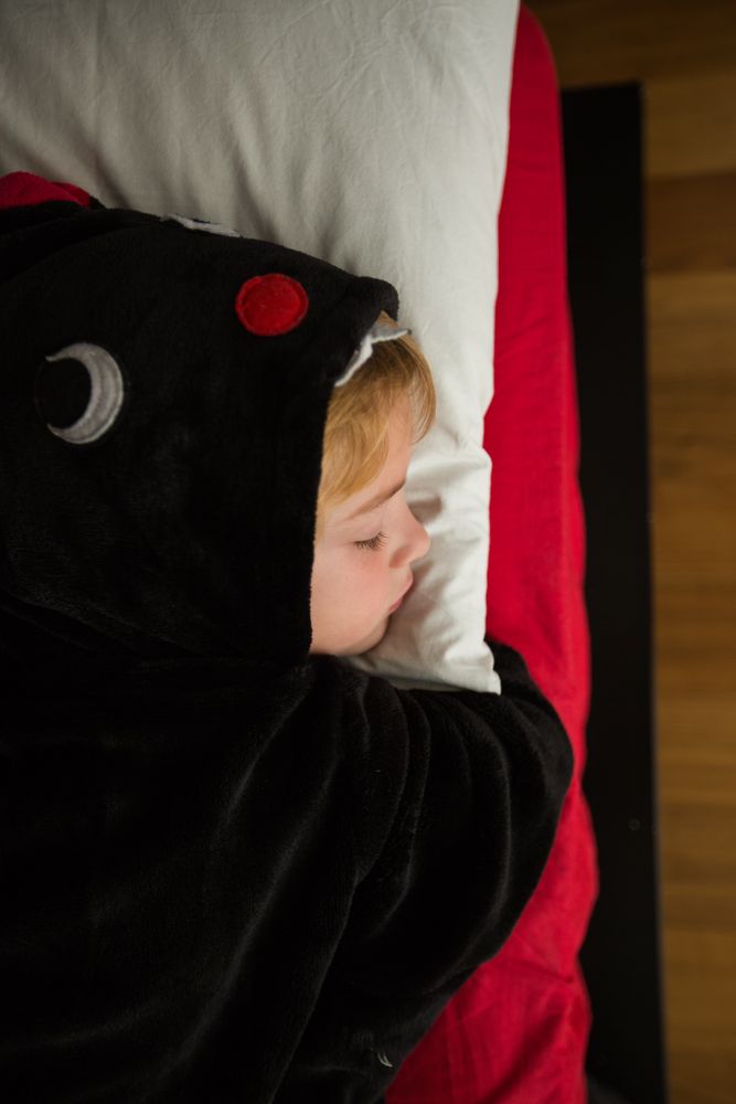 Boy in unicorn pajama sleeping in bed