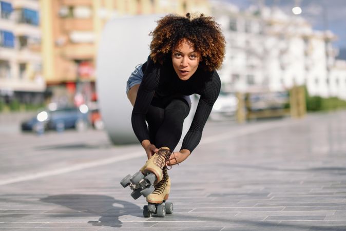 Smiling woman with afro doing one leg tricks on roller skates