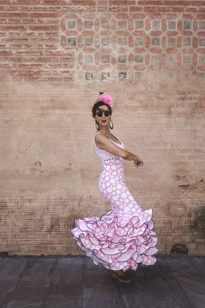 Passionate woman in flamenco dress dancing on street