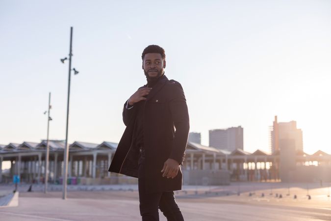 Black man looking around outdoors with sunset behind him