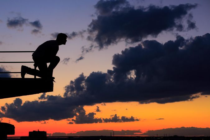 Male pretending to dive off ledge at dusk