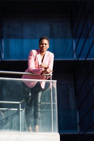 Satisfied woman in smart business attire leaning outside building looking at camera