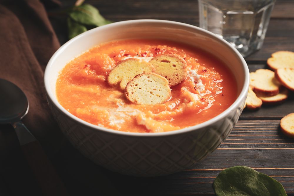 Bowl of cosy pumpkin soup on table with glass of water
