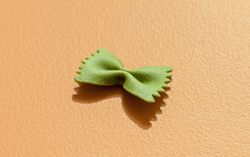 Spinach farfalle pasta minimalist on an orange table