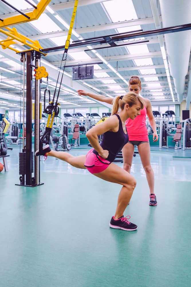 Woman doing lunges with elevated back leg with trainer