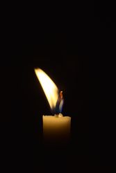Side view of candle flame blowing in the dark