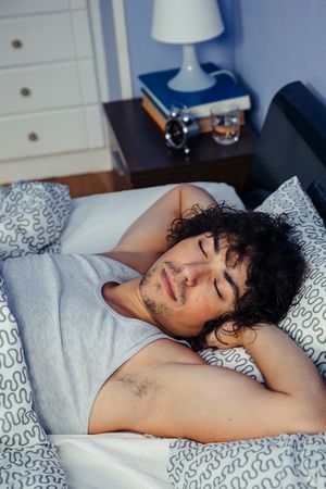 Man sleeping on his back in bed at home