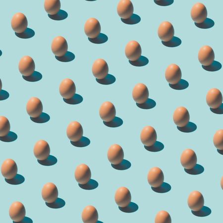 Pattern made of brown eggs on pastel blue background