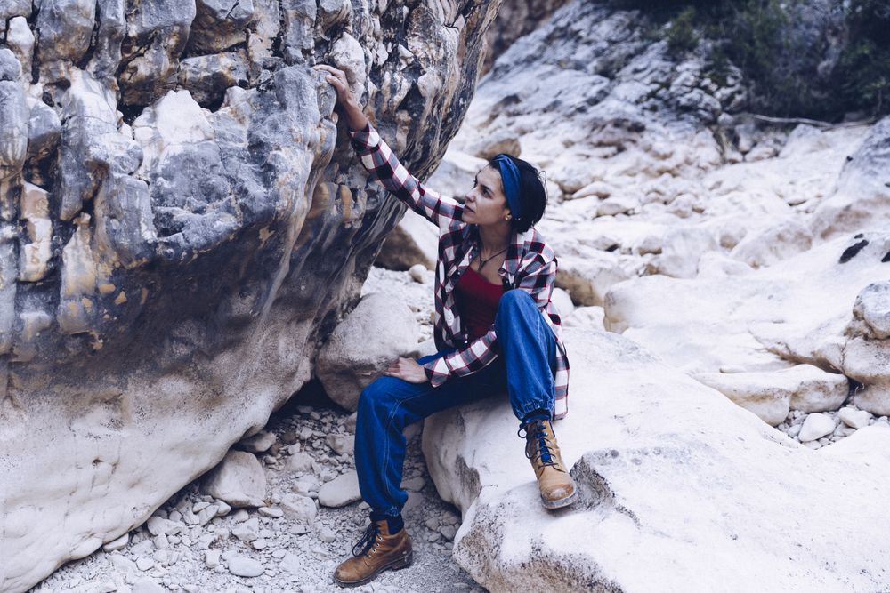 Positive woman sitting on stone