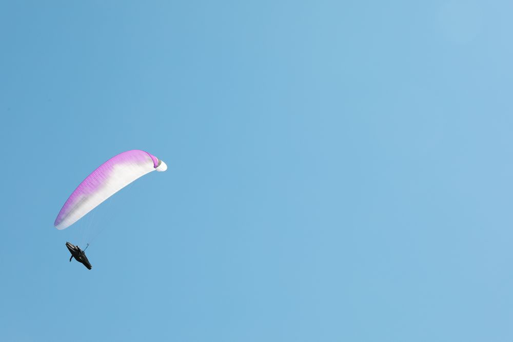 Skydiver with a pink parachute flies across the blue sky