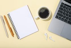 Top view banner of laptop, pens, coffee, cactus, earbuds and  notebook with blank page for writing