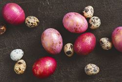 Top view of pink and gold eggs mixed with quail eggs on dark background