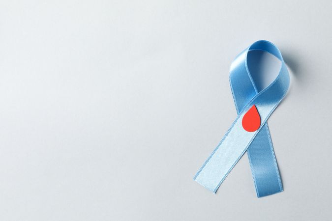 Diabetes. Blue awareness ribbon with decorated blood drop on light background