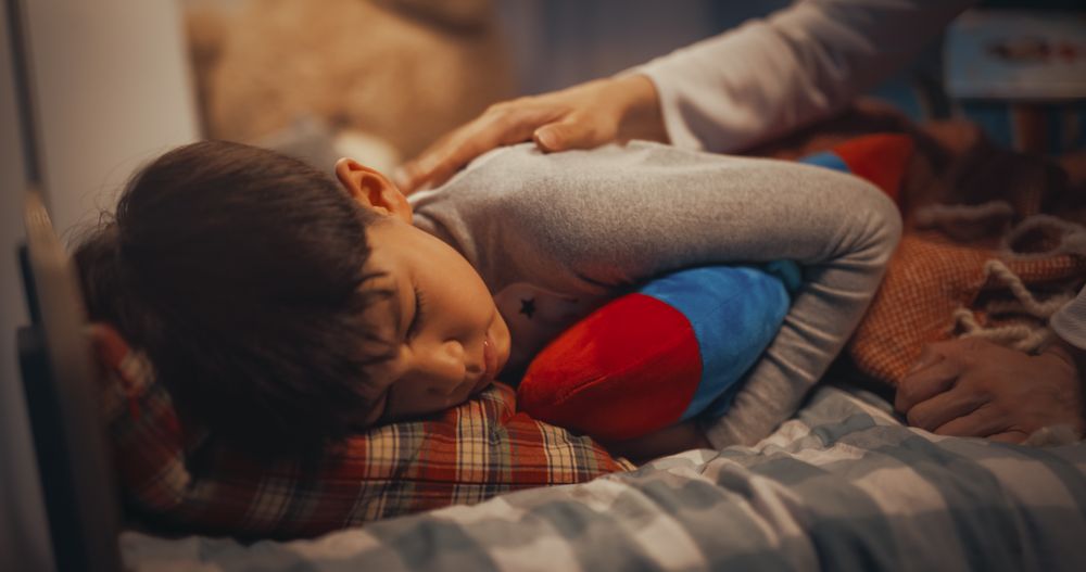 Korean Young Father Caring for His Cute Son, Putting Him to Sleep in Bed at Home in the Evening.