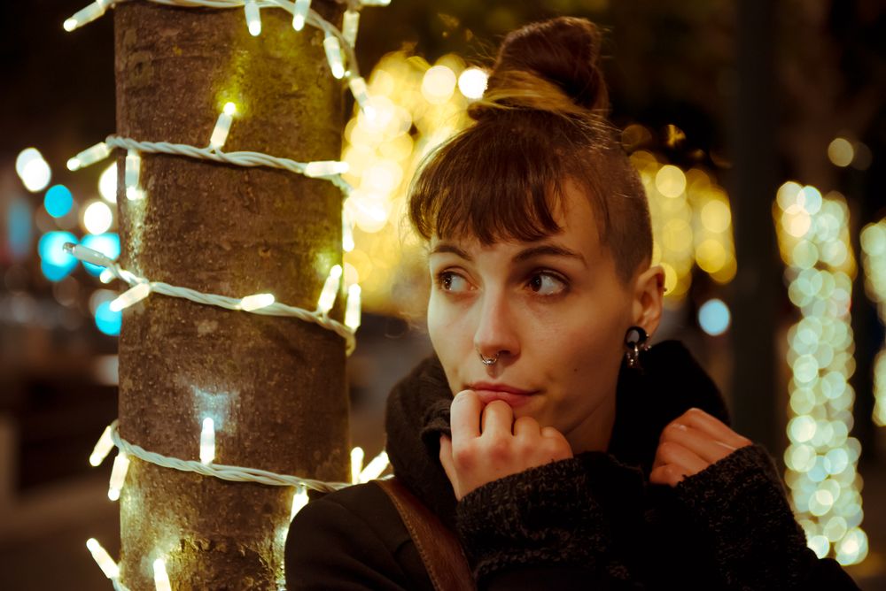 Woman in trendy outfit sitting near a Christmas tree