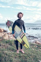 Smiling sportsman standing at seaside with surfboard