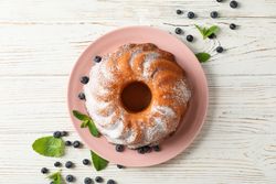 Cake with powder sugar and blueberry on wooden background, top view