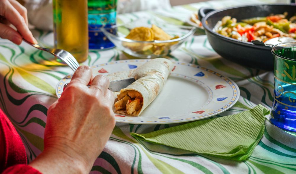 Woman rolling mexican fajita on the plate